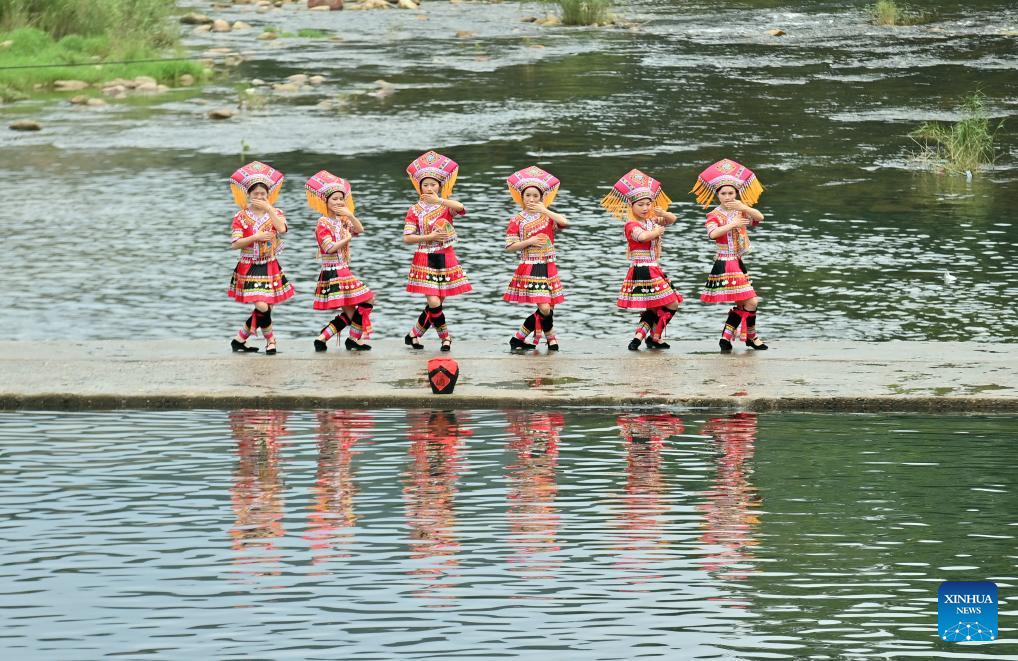 Penduduk kampung menari di atas laluan batu di atas sungai di Perbandaran Wangdong di Kaunti Autonomi Rongshui Miao di Wilayah Autonomi Guangxi Zhuang, selatan China, 18 Ogos 2024. Sejak beberapa tahun mutakhir, Perbandaran Wangdong telah memanfaatkan sumber airnya yang banyak untuk menggalakkan daya hidup luar bandar. Disokong oleh "bantuan berpasangan" dari Bandar Lianjiang di Provinsi Guangdong, perbandaran itu berjaya menganjurkan pertandingan sukan air, nyanyian duet lagu gunung dan aktiviti bertemakan warisan budaya tidak ketara di sekolah. Inisiatif ini bertujuan untuk membina jenama "budaya air" dan memajukan pembangunan pelancongan budaya etnik. (Xinhua/Huang Xiaobang)